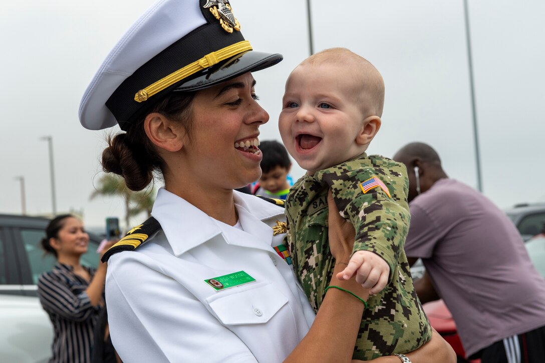 A sailor holds a smiling baby.