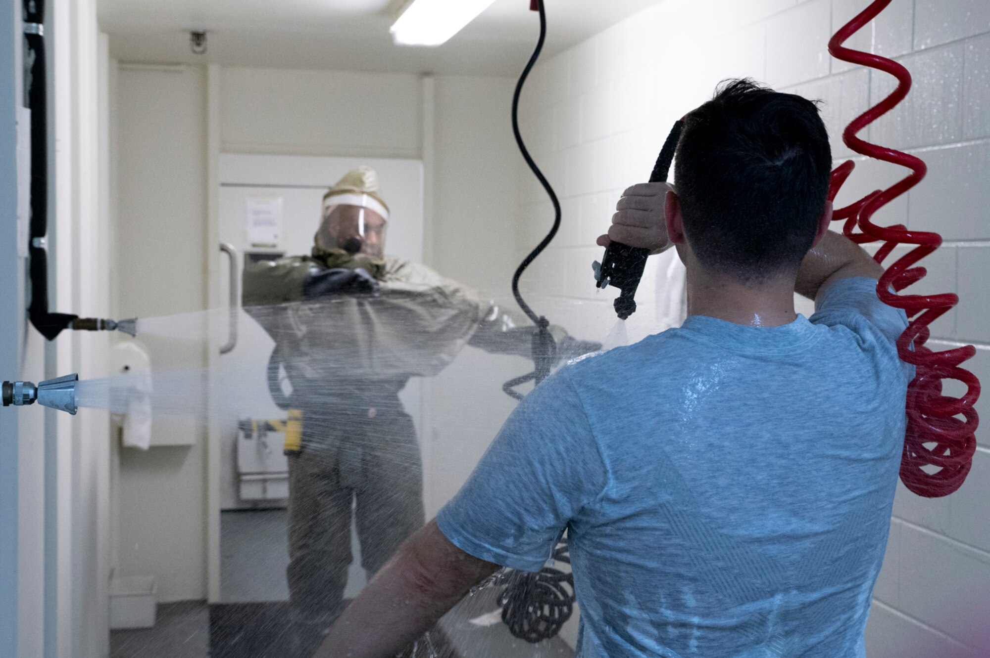 An Airman assigned to the 51st Medical Group, instructs a patient through decontamination procedures as part of a base-wide training event at Osan Air Base