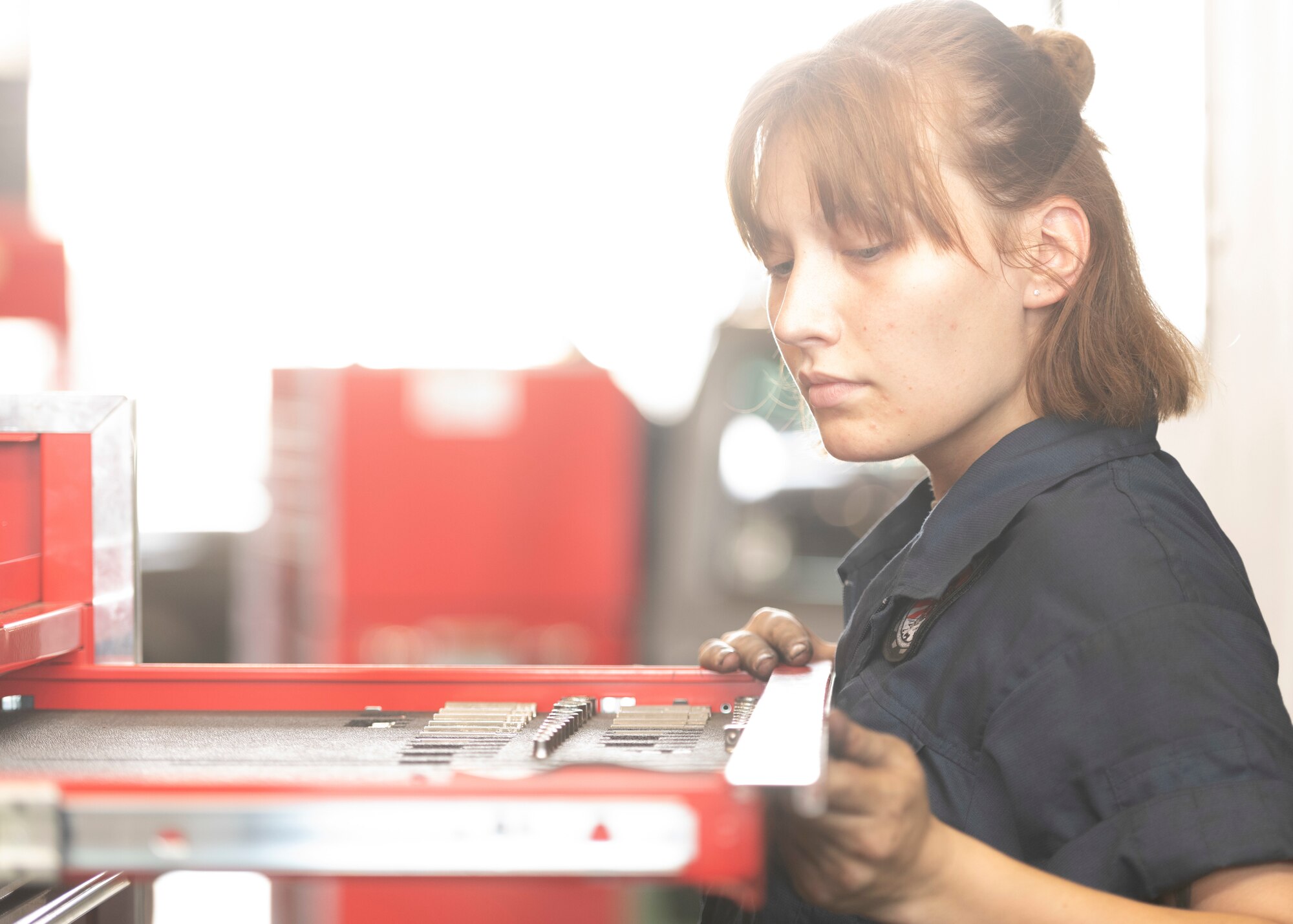 Airman 1st Class Maddison Stockman, 374th Logistics Readiness Squadron Vehicle Maintenance Flight apprentice, selects a tool for vehicle repair work at Yokota Air Base, Japan, Aug. 17, 2022.
