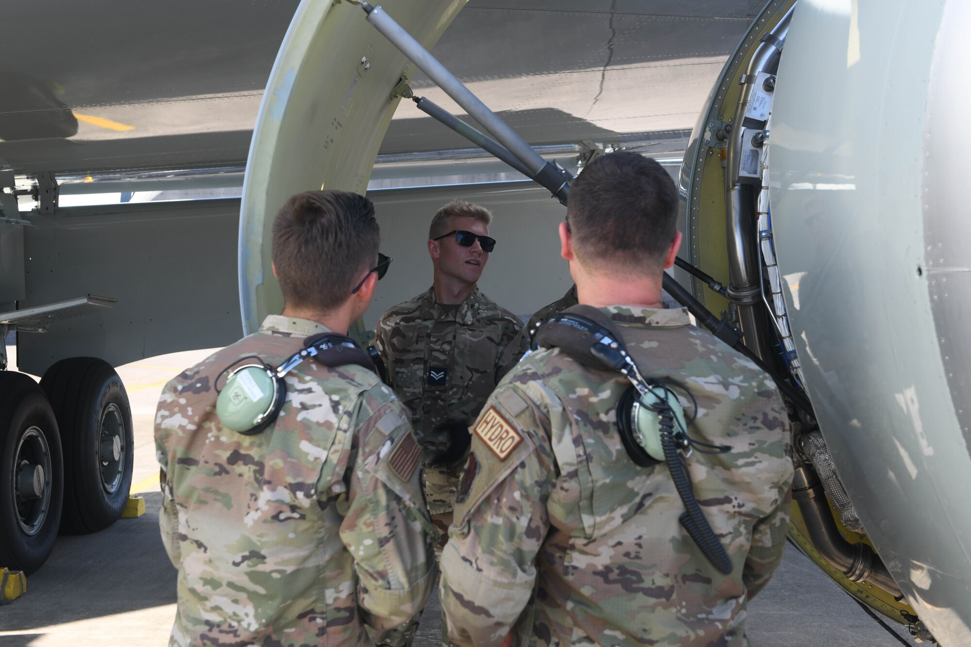 Airmen and an aviator perform routine maintenance on an aircraft.