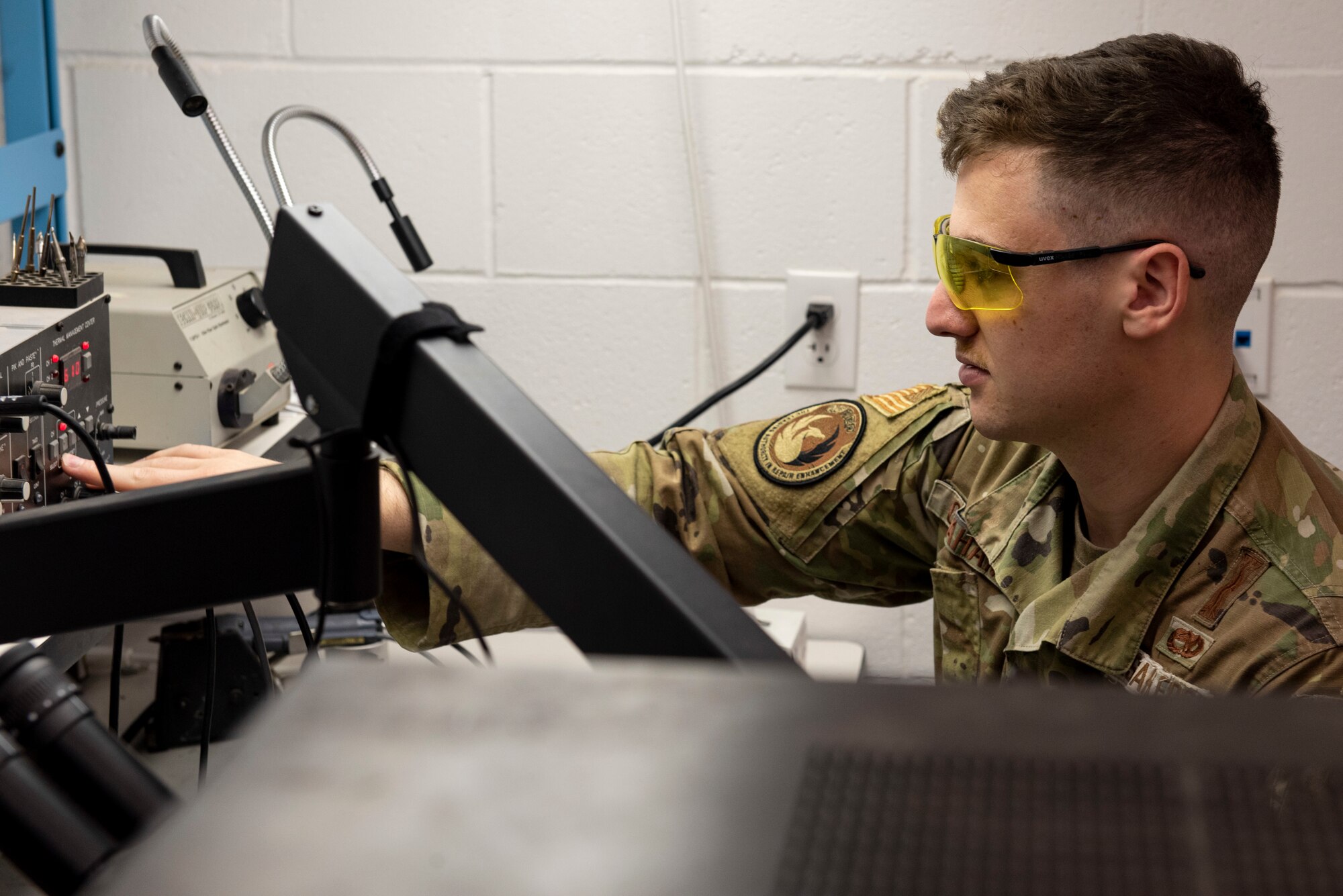 A man in green ocps turns on a black process control station.