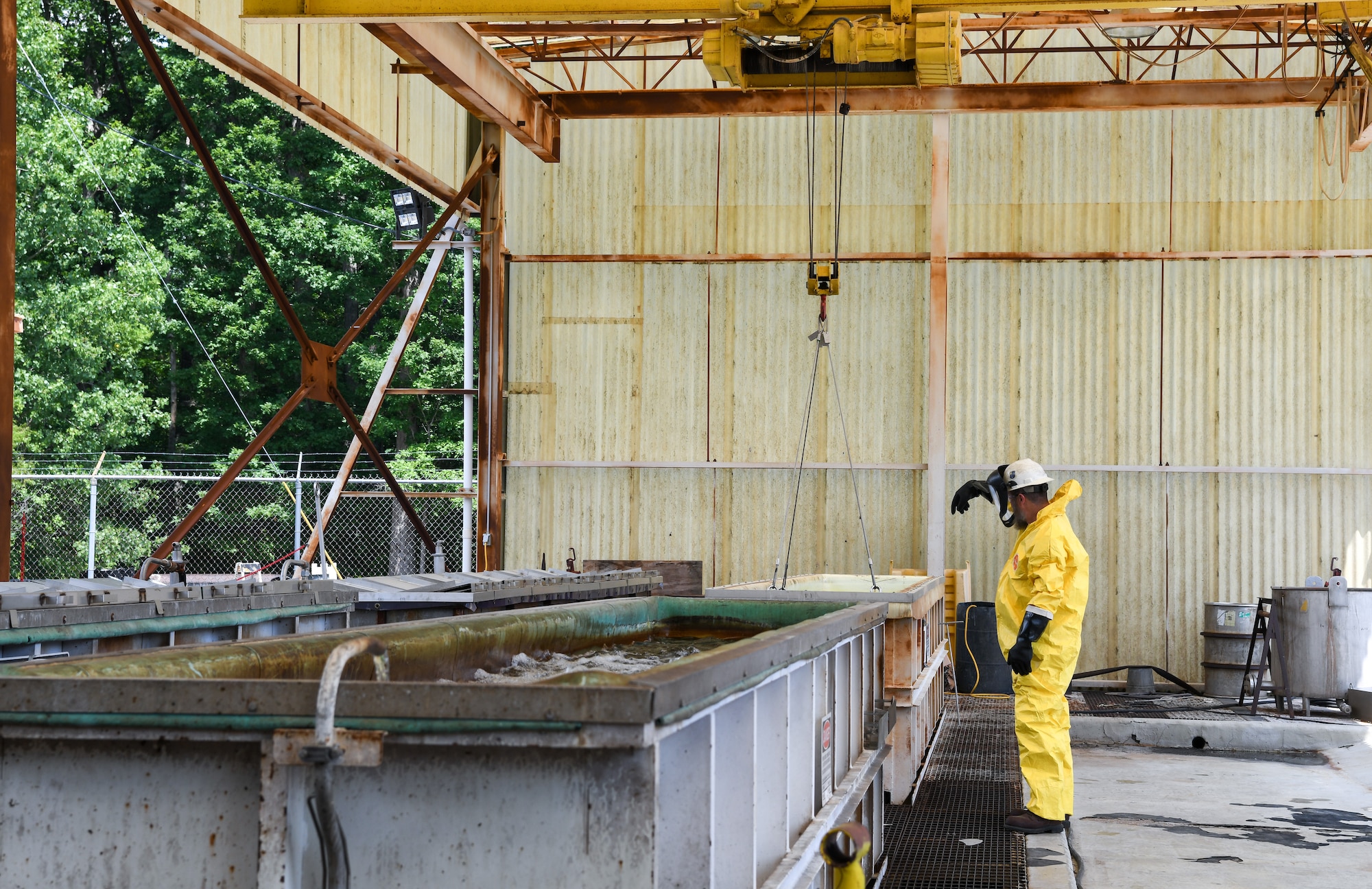 Worker in yellow Tyvek suit directing crane operations