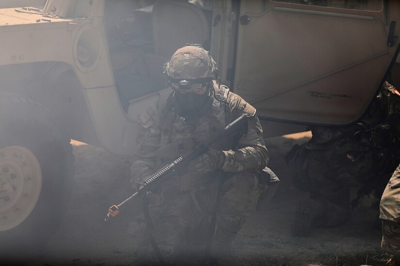 A U.S. Army Reserve Soldier, shielded by a High Mobility Multi-Purpose Wheeled Vehicle, prepares to return fire on insurgents during a complex simulated indirect fire attack with Chemical, Biological, Radiological, and Nuclear agents during convoy operations lane training at the CSTX 86-22-02 at Fort McCoy, Wisconsin, August 16, 2022.