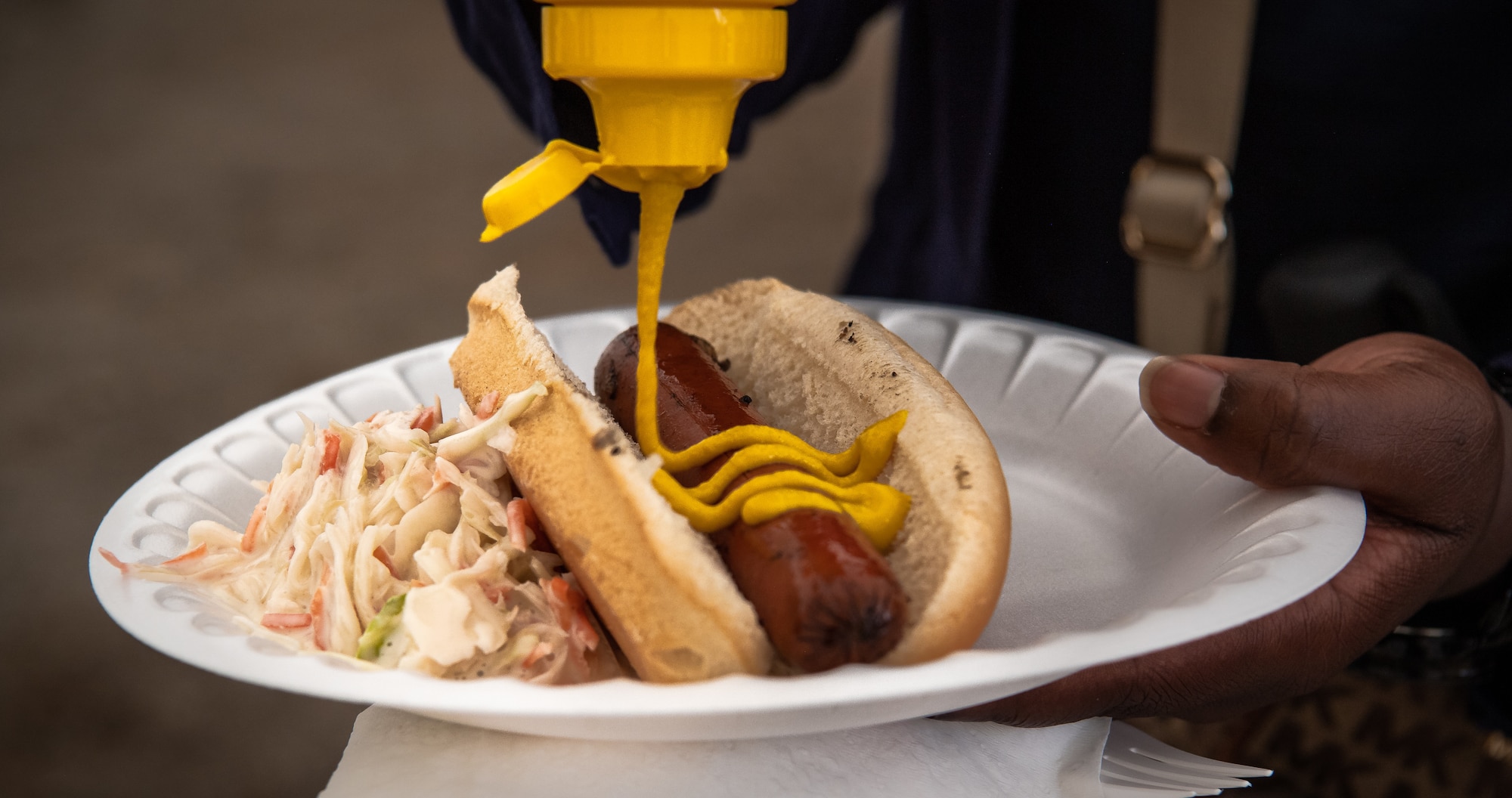 U.S. Air Force Master Sgt. Sabrina Valentine, 435th Air Ground Operations Wing Commanders Executive Administration superintendent, prepares her hot dog during a 435th AGOW Family Fun Event at Ramstein Air Base, Germany, Aug. 18, 2022. Airmen and their families enjoyed fellowship with their peers as well as food and games. (U.S. Air Force photo by Airman 1st Class Jared Lovett)
