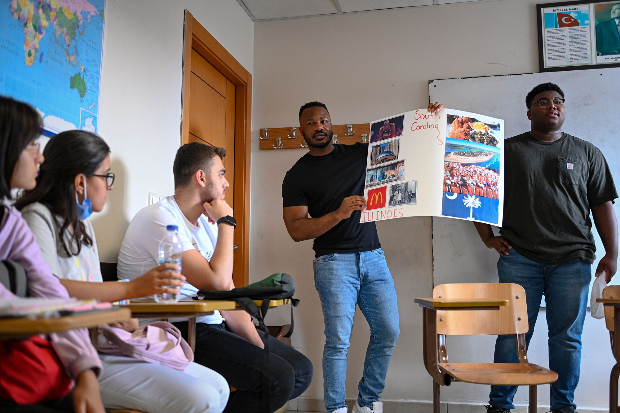 Senior Airman Marcellous Butler (center), a commander support staff personalist assigned to the 39th Air Base Wing (ABW), and Senior Airman Justin Richardson (right), a combat arms instructor assigned to the 39th Security Forces Squadron, give a brief presentation on American culture at the Turkish-American Association (TAA) in Adana, Turkey, Aug. 23, 2022.