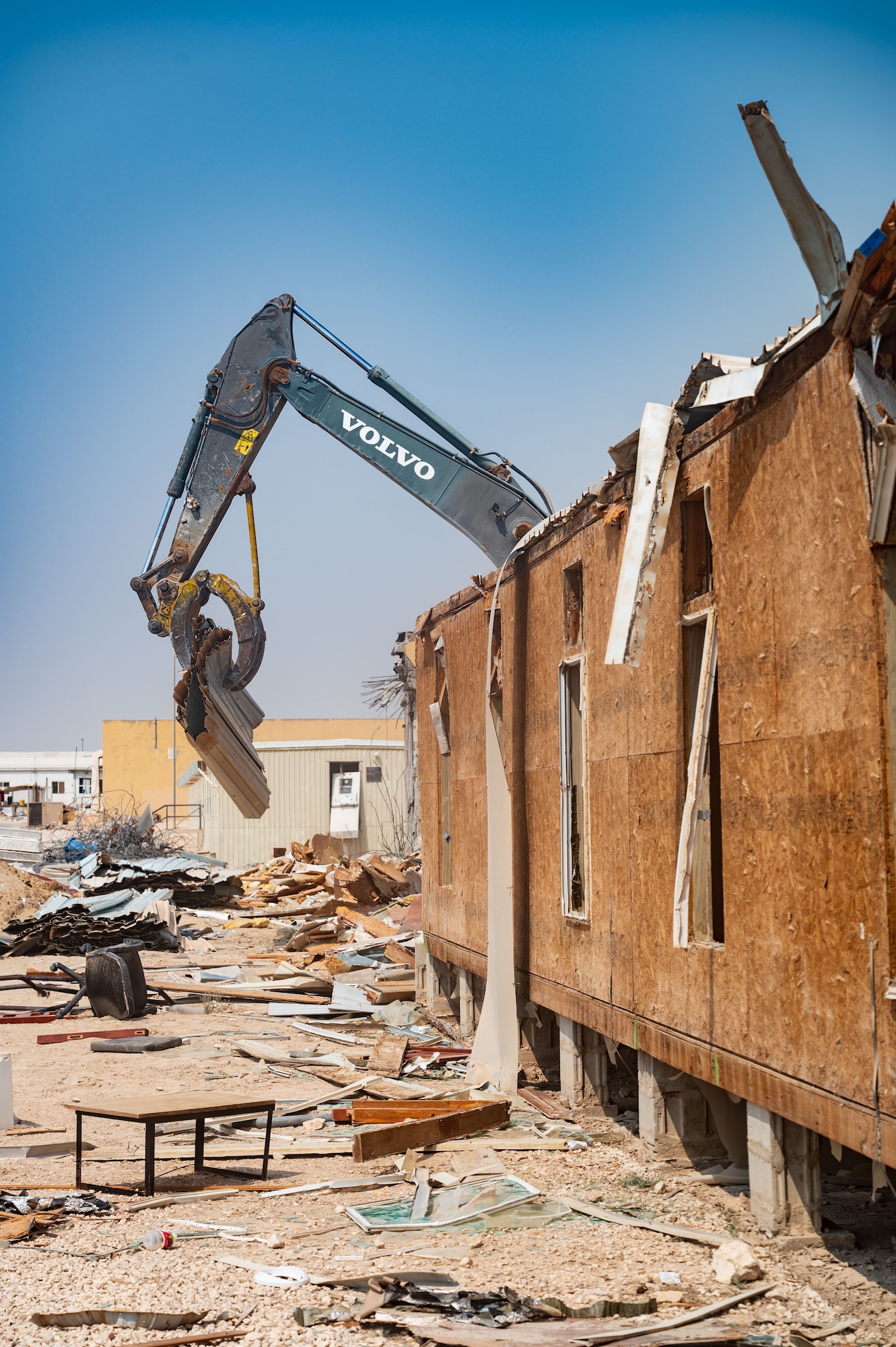 An excavator tears off a trailer roof section, Aug. 22, 2022 at Al Udeid Air Base, Qatar. Each material was sorted into various piles to be sent off later for recycling.  (U.S. Air Force photo by Staff Sgt. Dana Tourtellotte)