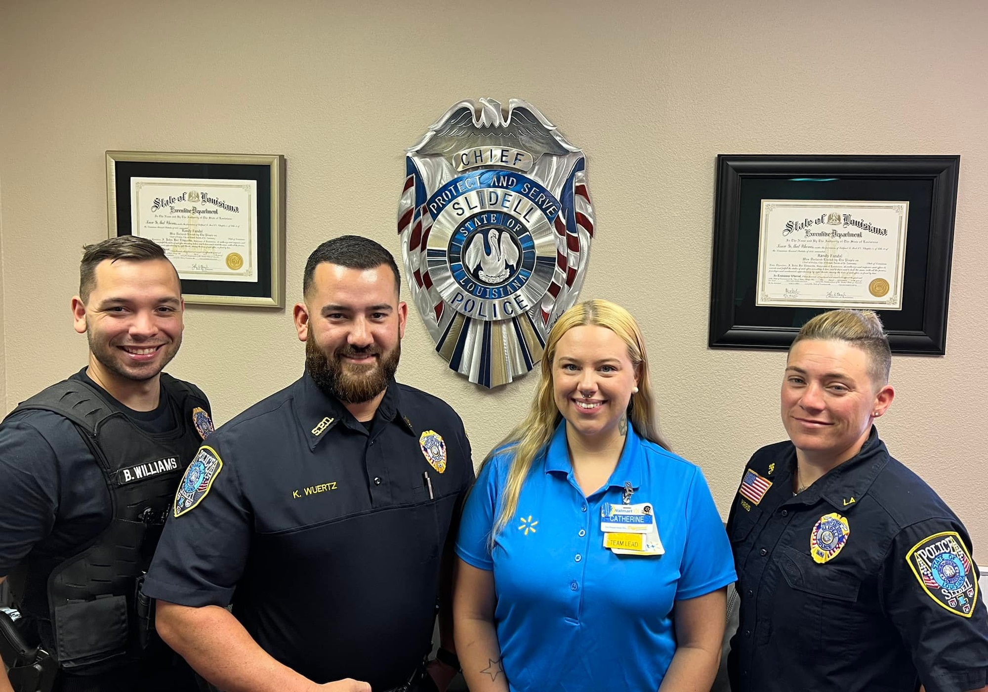 Three police officers flank a Walmart employee