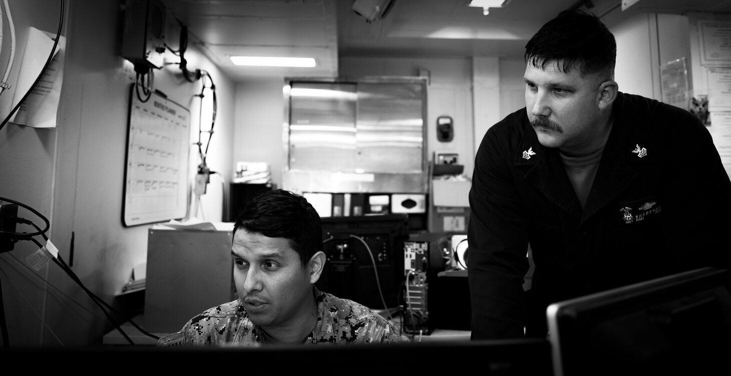 Two corpsman look at a computer screen