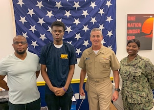 WOODBRIDGE, Va. (Aug. 16, 2022) From left, Dumerene Cornelius, his son and Navy recruit Miracle Cornelius, Rear Adm. Pete Garvin, commander, Naval Education and Training Command (NETC), and Aviation Boatswain’s Mate (Handling) 2nd Class Chanika Cato, a recruiter, pose for a photo at Navy Recruiting Station Woodbridge, Virginia, Aug. 16, 2022.  Garvin visited the recruiting station to talk with recruiters about their mission to inform, attract, influence and hire the highest quality candidates from America's diverse talent pool. As the owner of the Force Development pillar within MyNavy HR, NETC recruits, trains and delivers those who serve the nation, taking them from "street to fleet" by transforming civilians into highly skilled, operational, and combat ready warfighters. (U.S. Navy photo by Lt. Steve Nieto)