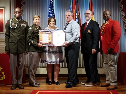 Amy Jones, of Sterling, Illinois, third from left, spouse of Sgt. 1st Class Terry Jones II, and retired Sgt. 1st Class Terry Jones, Sr., third from right, Jones’ father, accept the Transportation Corps Hall of Fame induction certificate from, from left, Command Sgt. Maj. Randy Brown, Transportation Corps Command Sergeant Major, Col. Beth Behn, Chief of Transportation, Maj. Gen. (retired) Charles Fletcher, Honorary Colonel of the Transportation Corps Regiment, and Command Sgt. Maj. (retired) Cedric Thomas, Honorary Sergeant Major of the Transportation Corps Regiment, during the induction ceremony July 29 at Fort Lee, Virginia.
