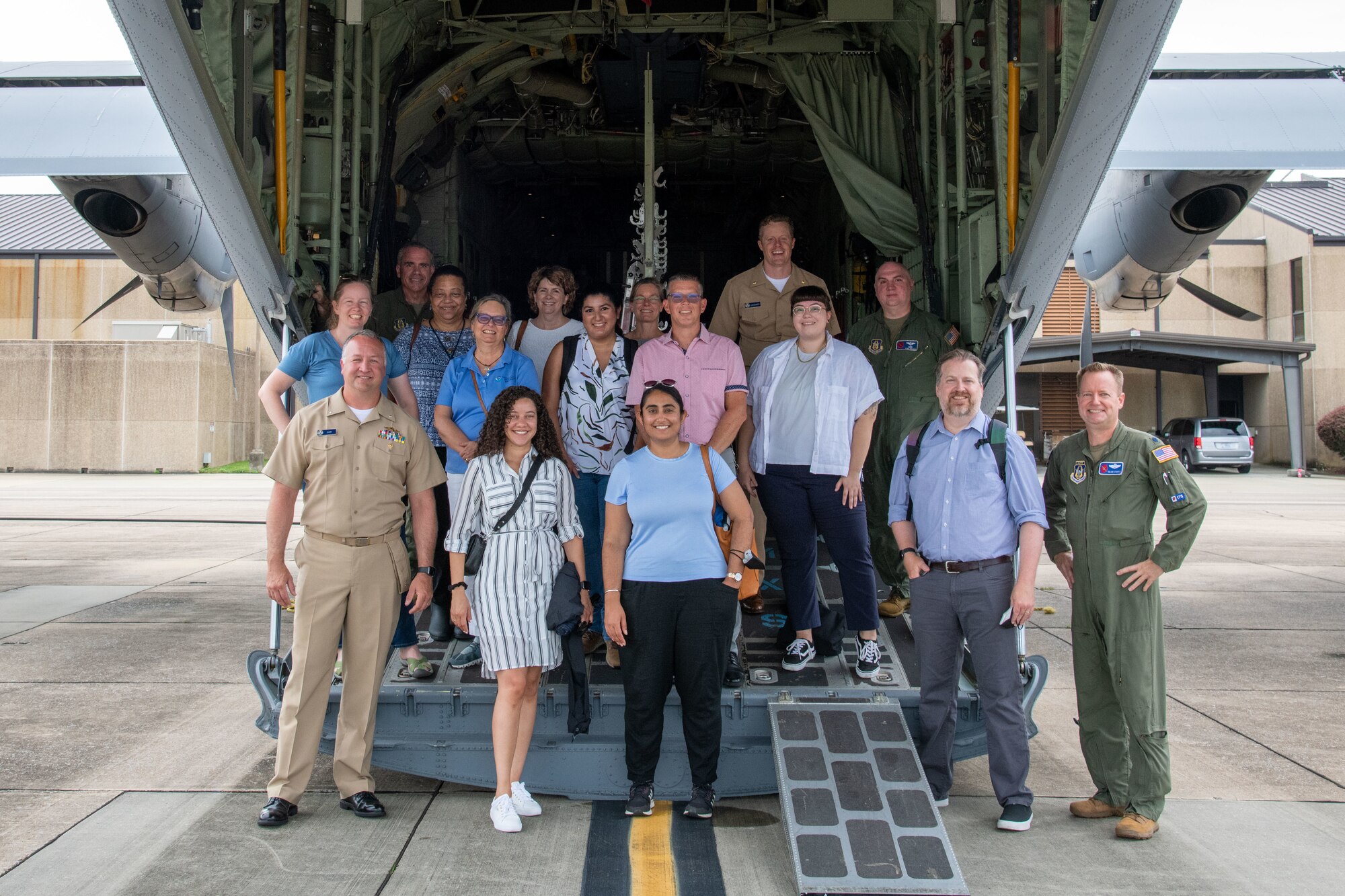 A group poses for a photo on the ramp of a WC-130J aircraft