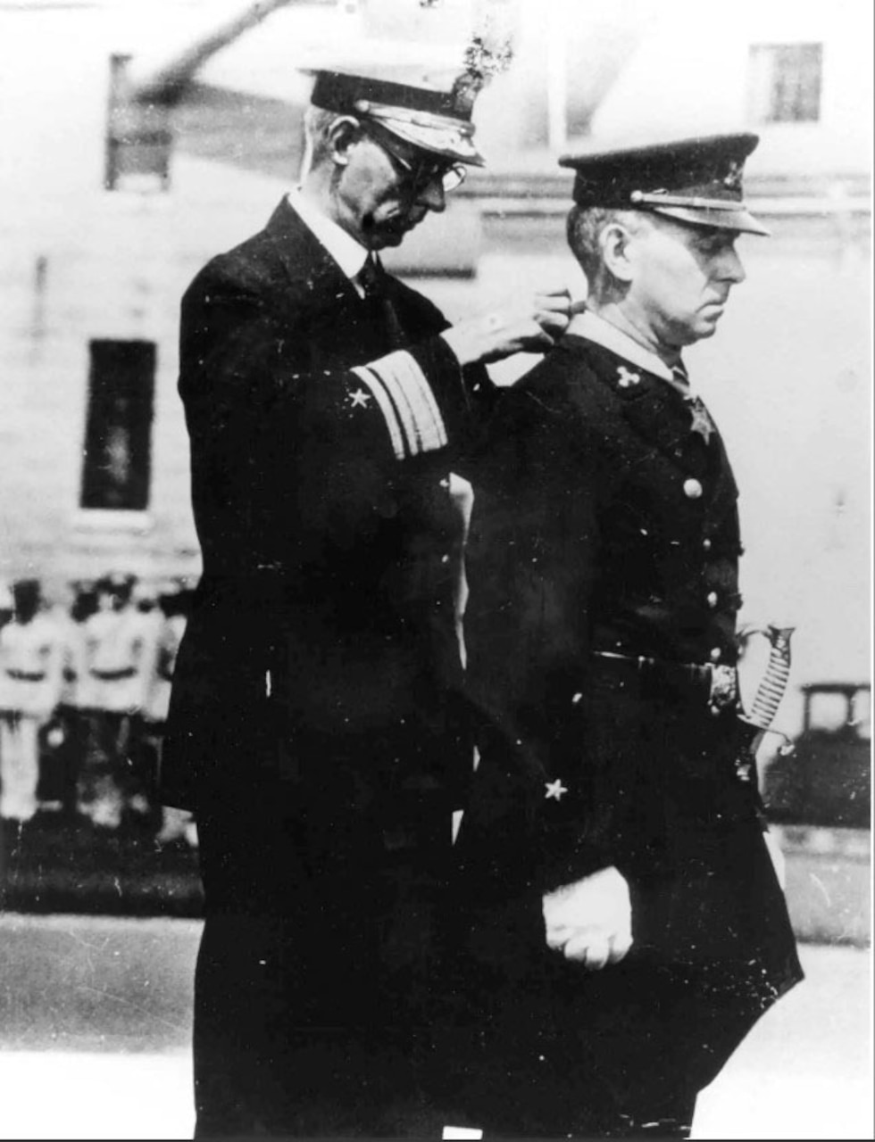 A man clasps a medal around another man’s neck.
