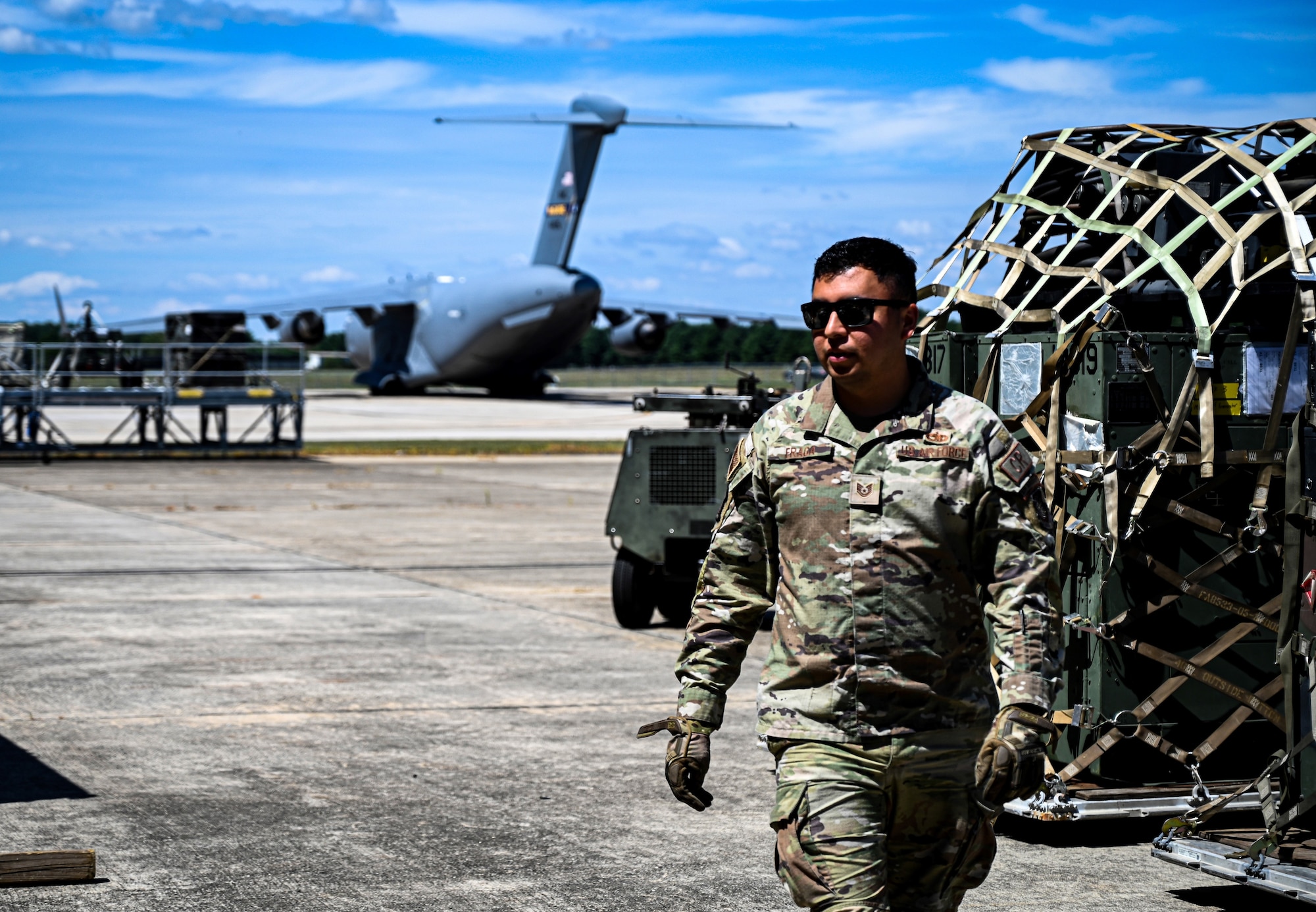 A U.S. Air Force Airman from the 321st Contingency Response Squadron walks past cargo awaiting to be loaded onto a C-17 Globemaster III during the Aerial Port of the Future Joint Capability Technology Demonstration at Joint Base McGuire-Dix-Lakehurst, N.J. August 16, 2022. The APoF JCTD improved the way personnel and cargo are processed and transported by applying new methods and technologies in a simulated deployment environment. (U.S. Air Force photo by Staff Sergeant Sabatino DiMascio)