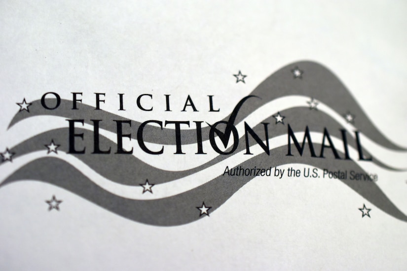 A close-up shot shows the logo on an official mail-in ballot.