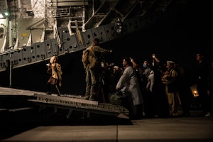 Photo of an Airman standing in front of an aircraft at night