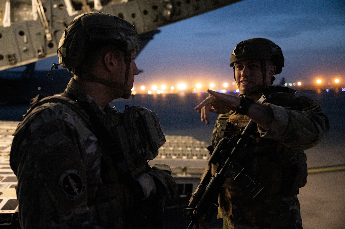 Two 379th Expeditionary Security Forces Squadron Airmen discuss the situation while standing watch over an aircraft at Hamid Karzai International Airport in Kabul, Afghanistan, Aug. 18, 2021, during Operation Allies Refuge. Approximately 124,000 Afghan citizens were evacuated from Kabul, Afghanistan, during OAR, one of the largest air evacuations of civilians in American history. (U.S. Air Force photo by Staff Sgt. Brandon Cribelar)