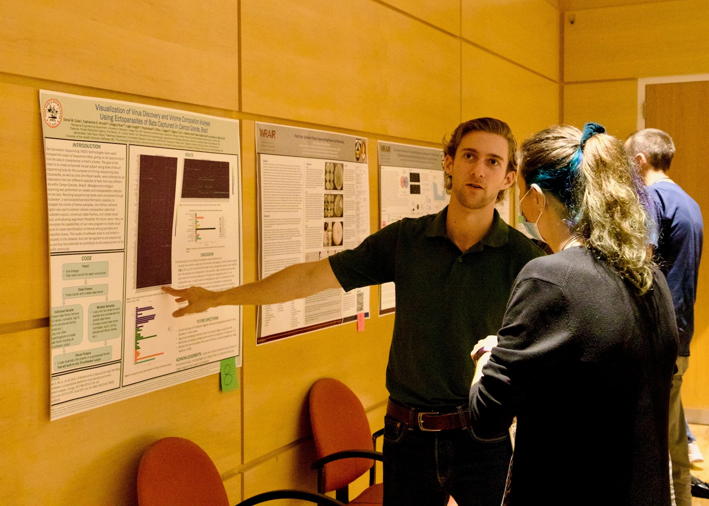 Daniel Coile, an intern with the Naval Research Enterprise Internship Program, explains findings from a research poster to Naval Medical Research Center (NMRC) staff. Interns from NMRC and Walter Reed Army Institute of Research presented on research they participated in at an annual joint STEM Expo poster session, which marked the final day of the summer program. (U.S. Navy photo by Sidney Hinds/Released)