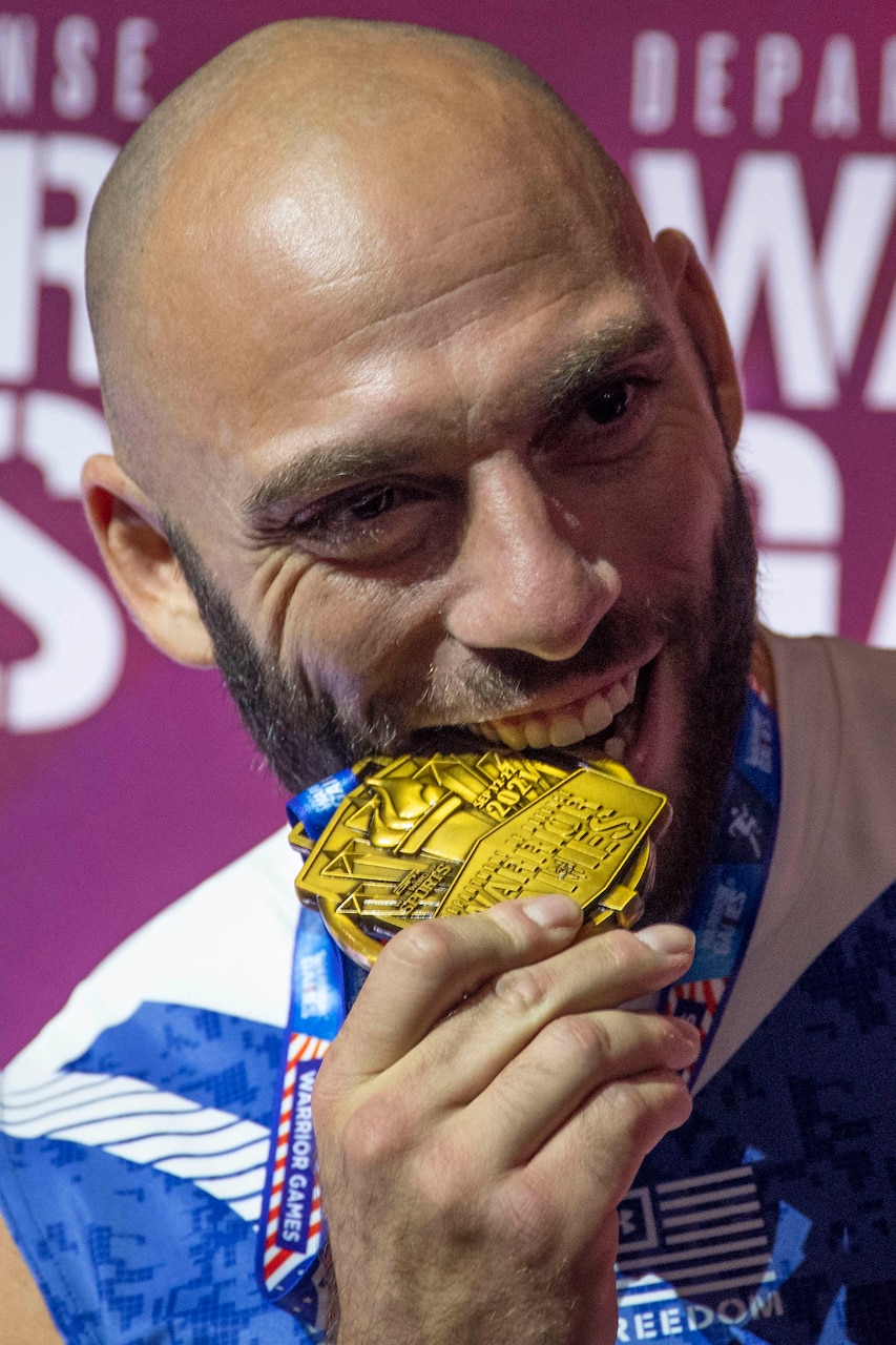 An athlete bites into a gold medal.