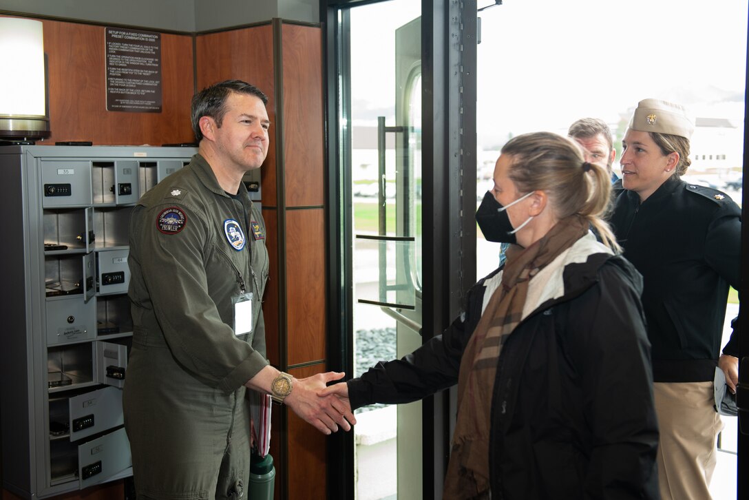 Photo of U.S. Navy CDR Frank McBride shaking hands with members from the National Oceanic and Atmospheric Administration at the entrance of a building.