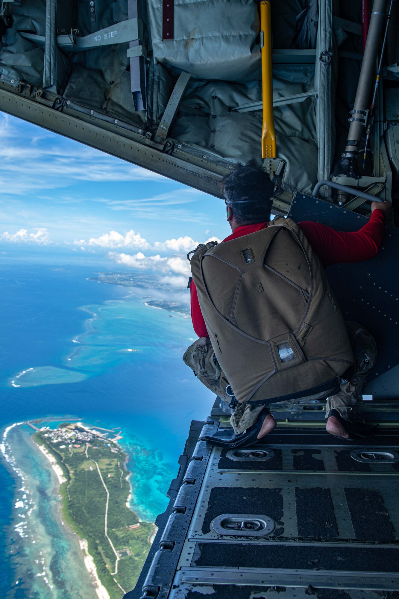 An Airman looks out at an island from the back of a plane