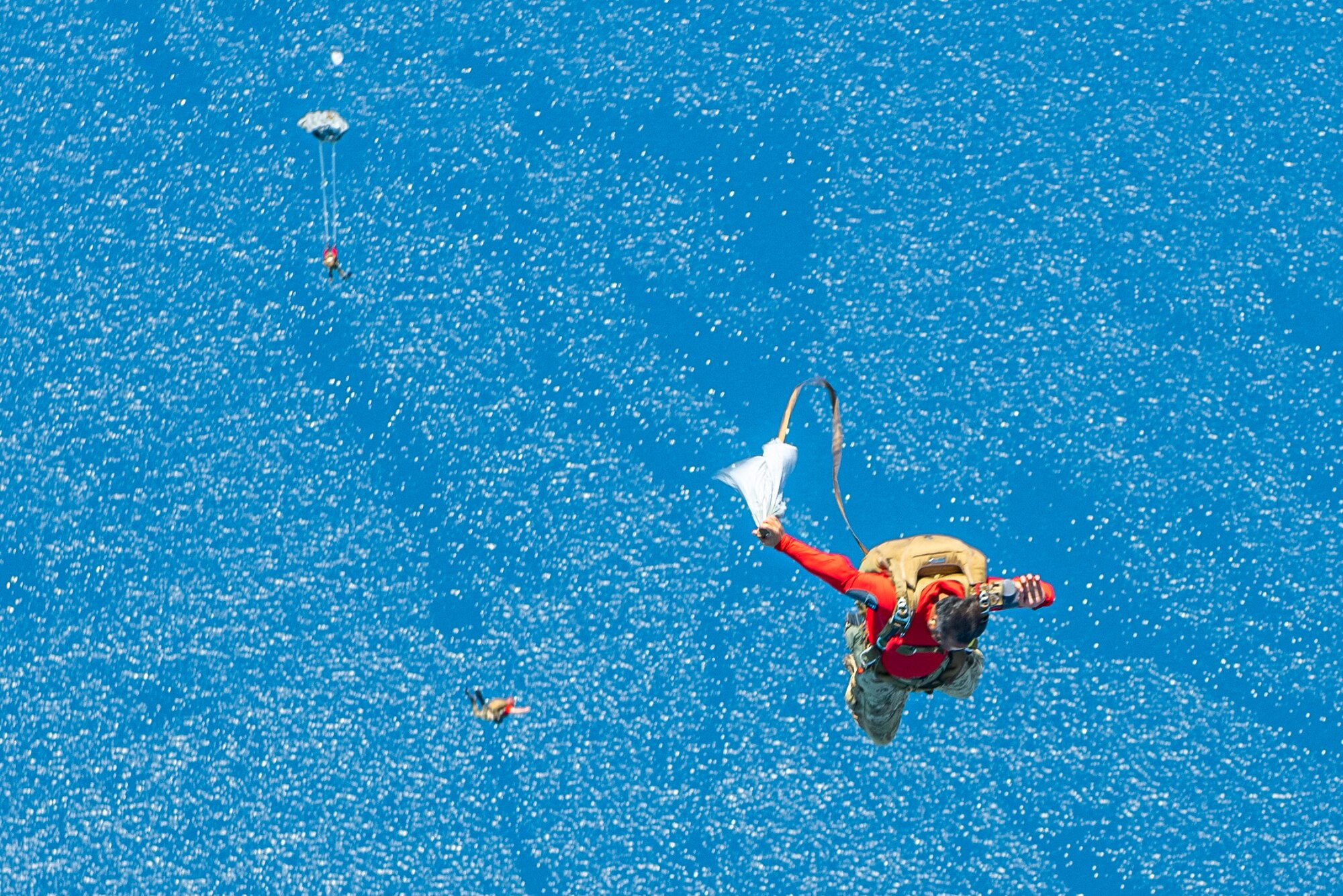 An Air Force member releases his parachute as he free falls towards the ocean