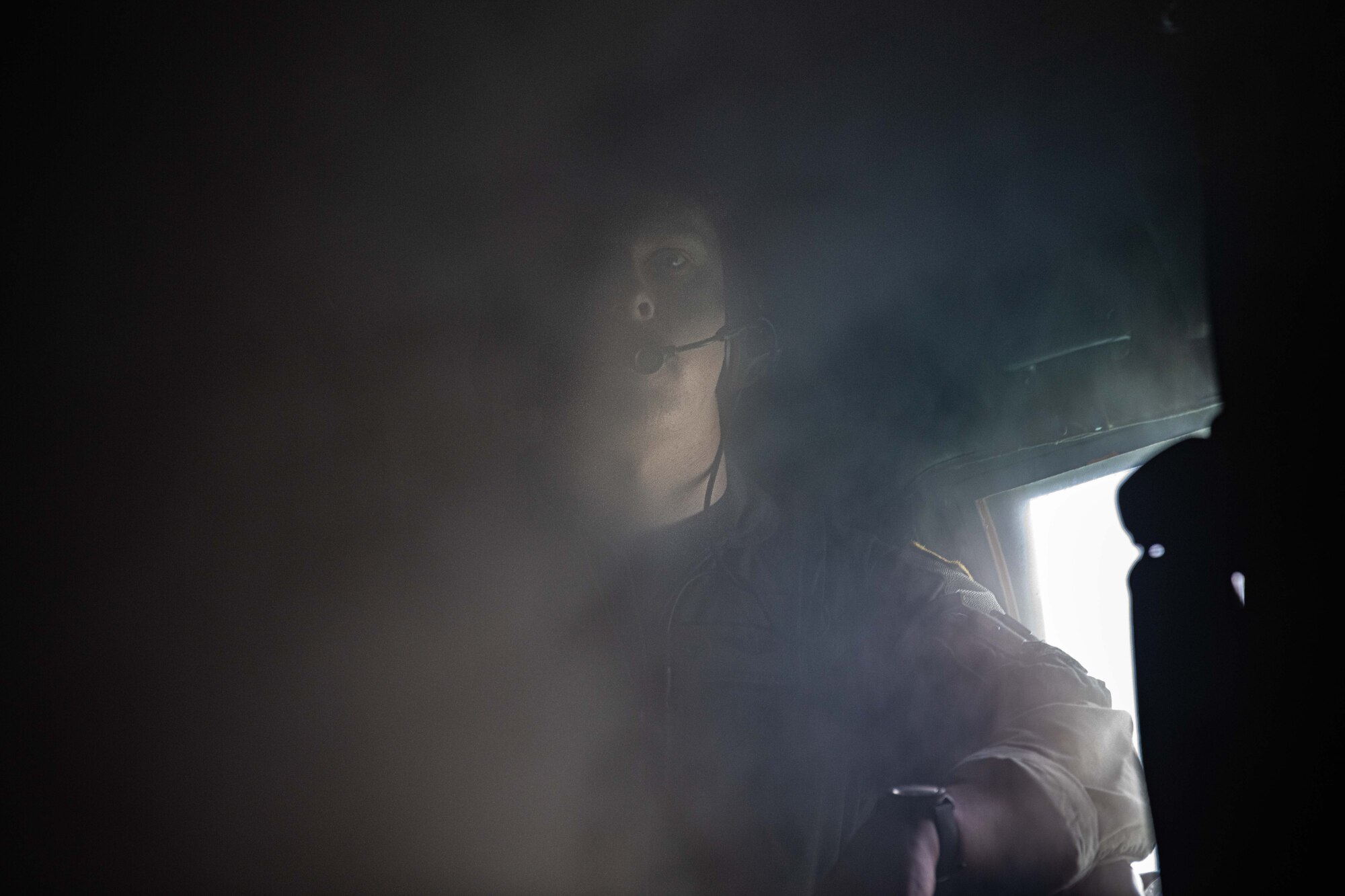 A member of the flight crew stares at the camera through the thick water vapor billowing in the cabin.