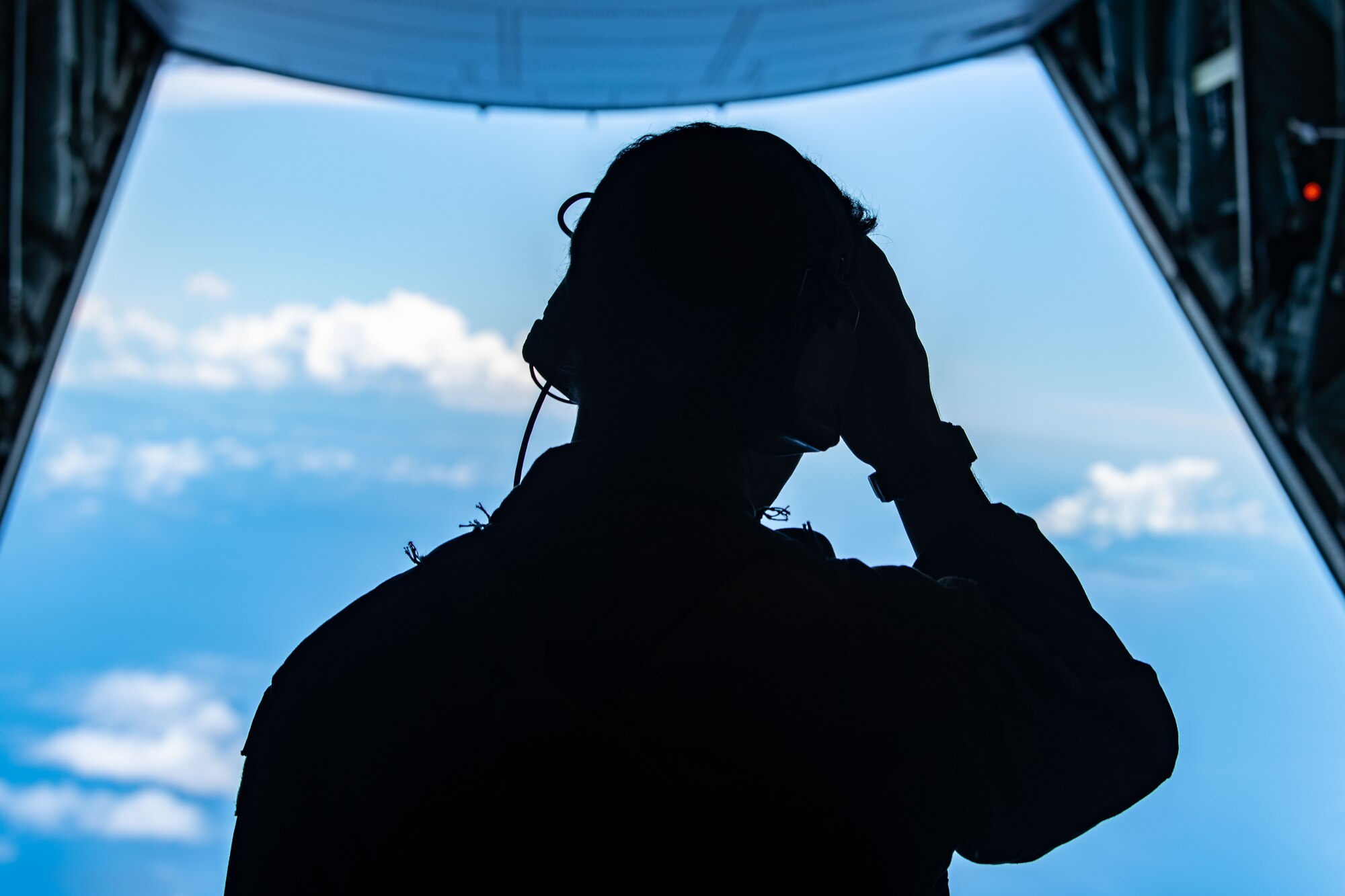A member of the flight crew stares out the back of the jet into the ocean.
