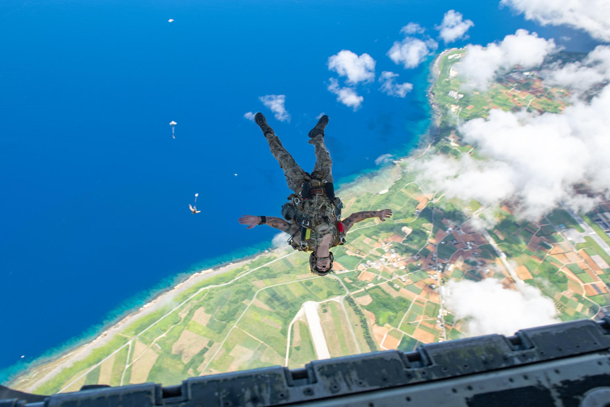 A Navy member does a backflip midair during a freefall above the coast of Japan.