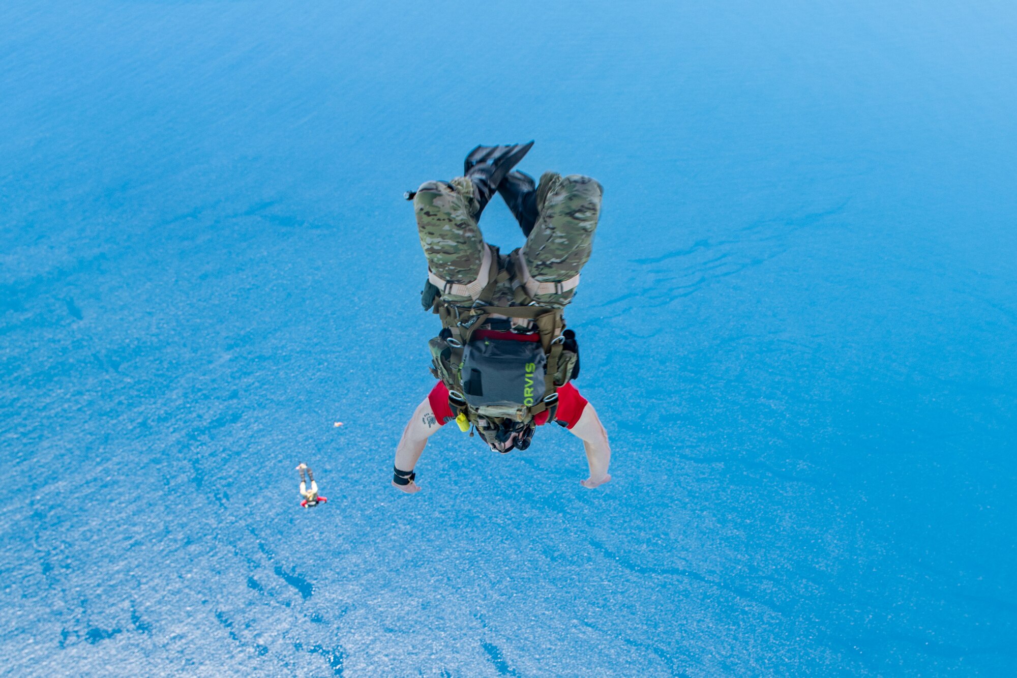 A military member jumps out over the ocean