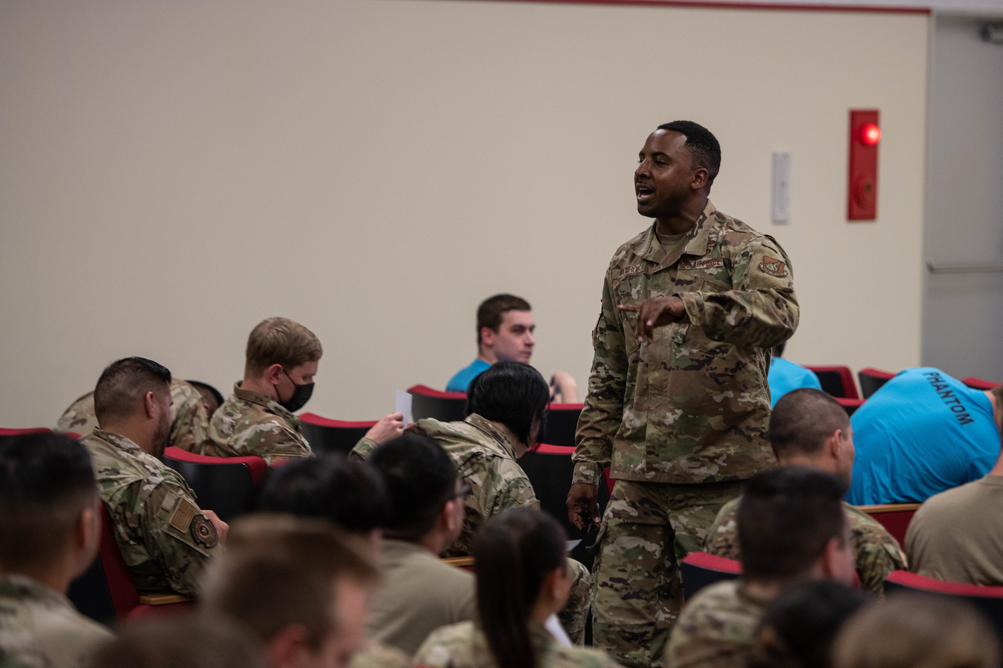 An Airman walks down the aisle while giving a presentation.