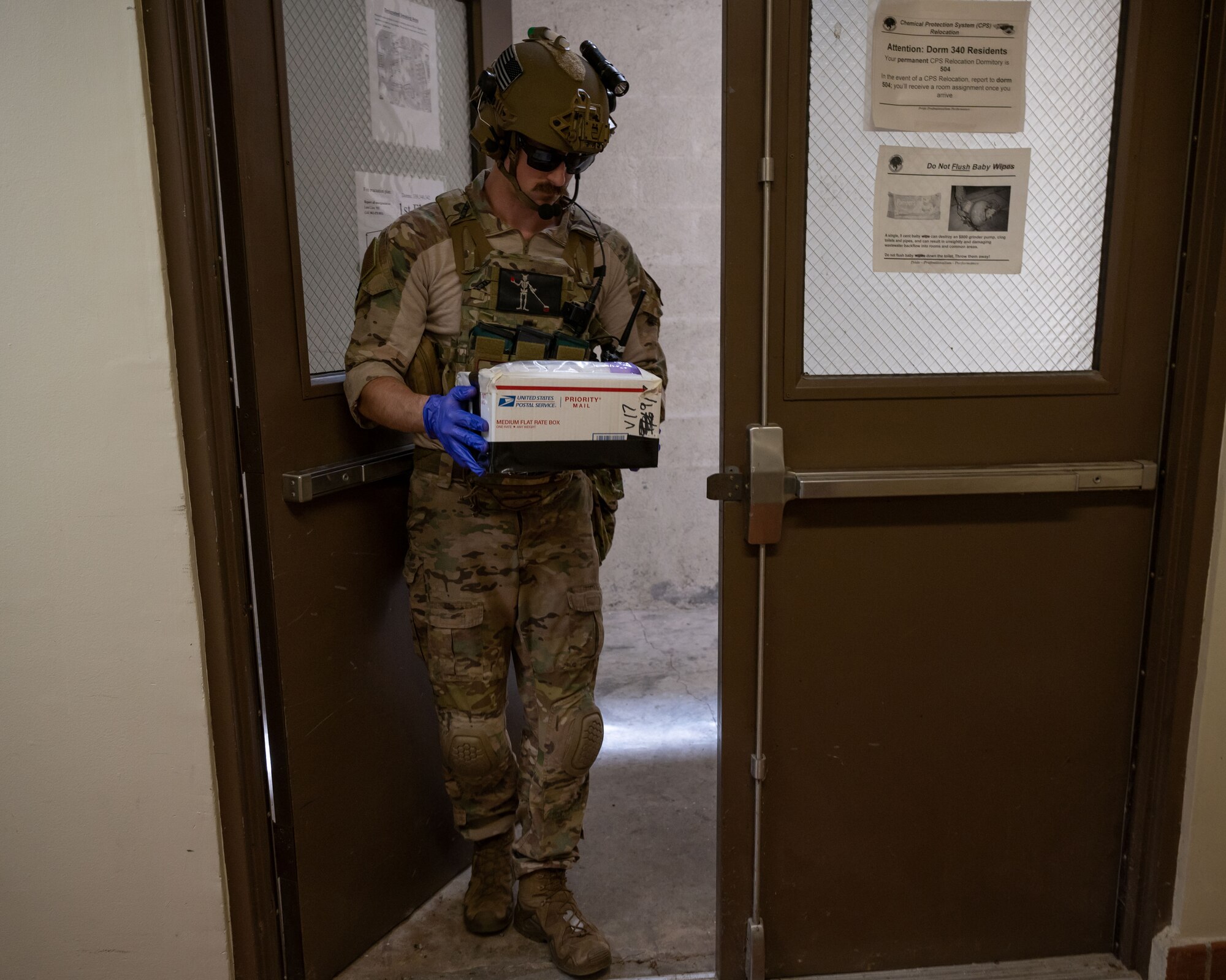 An Airman carefully walks out of the building with a simulated explosive package.