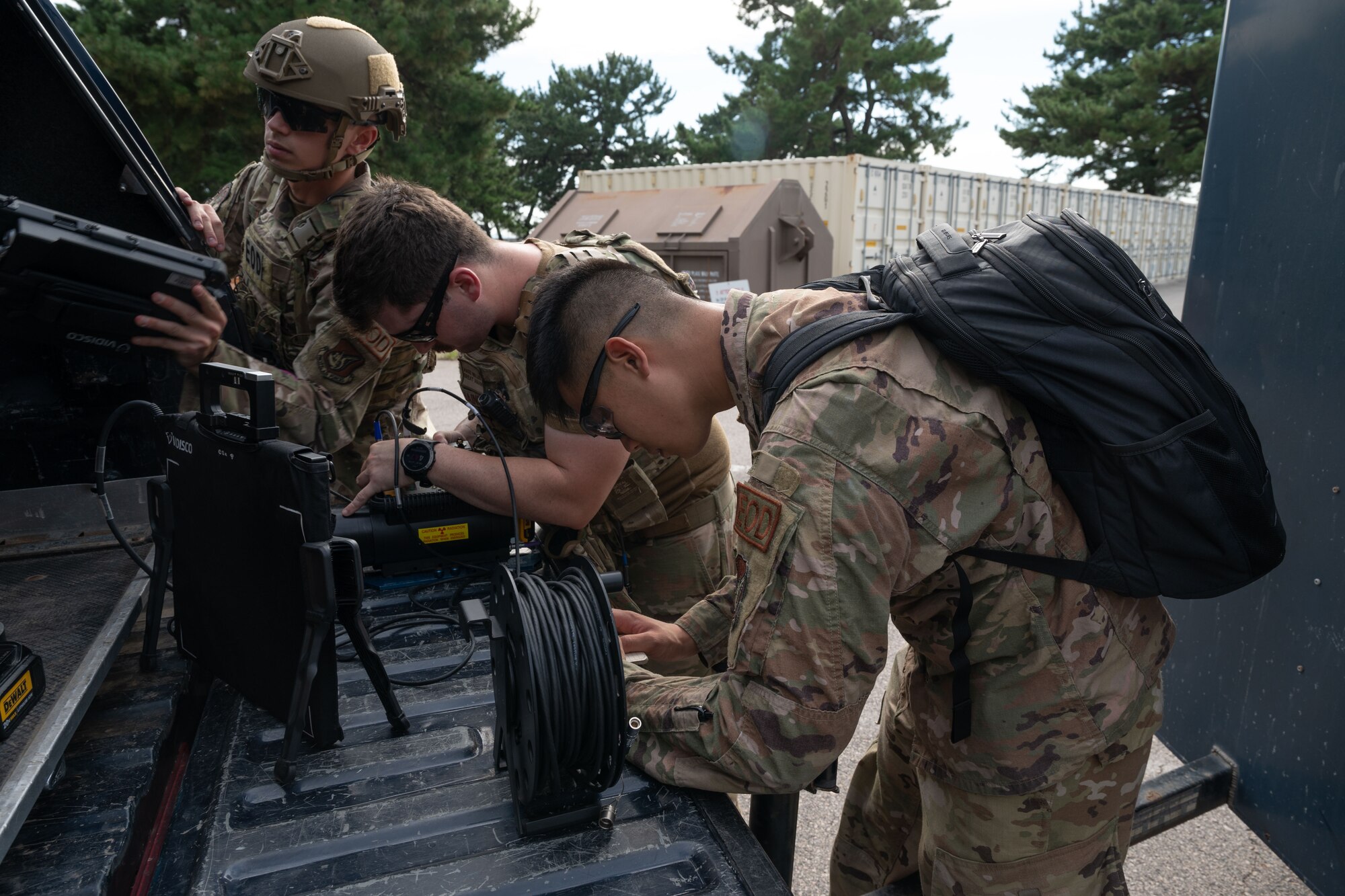 Three Airmen work together to prepare an x-ray generator.