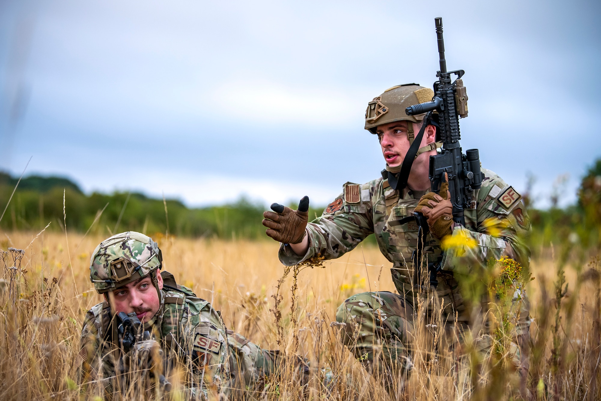 U.S. Air Force Senior Airman Ambrose Ross, right, 423d Security forces squadron police services, speaks with Airman 1st Class Daniel Richards, 423d SFS entry control operator, during a field training exercise at Stanford Training Area, England, Aug. 17, 2022. Instructors from the 820th Base Defense Group and 435th Security Forces Squadron Ground Combat Readiness Training Center, conducted the exercise to evaluate and bolster the combat readiness skills of the defenders from the 423d SFS. (U.S. Air Force photo by Staff Sgt. Eugene Oliver)