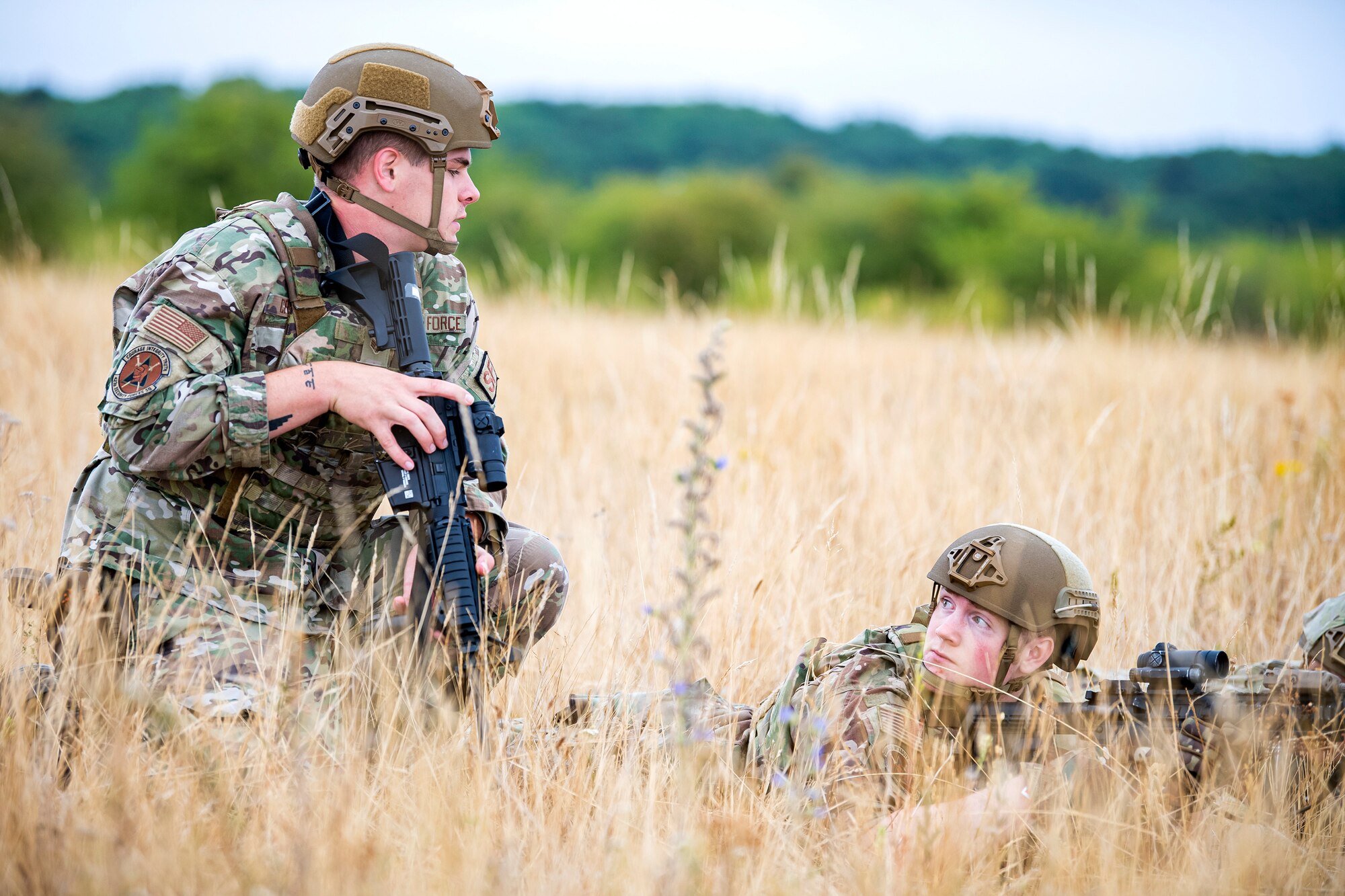 U.S. Air Force Senior Airman Joshua Cross, left, 423d Security Forces Squadron physical security, speaks with an Airman from the 423d SFS, during a field training exercise at Stanford Training Area, England, Aug. 17, 2022. Instructors from the 820th Base Defense Group and 435th Security Forces Squadron Ground Combat Readiness Training Center, conducted the exercise to evaluate and bolster the combat readiness skills of the defenders from the 423d SFS. (U.S. Air Force photo by Staff Sgt. Eugene Oliver)