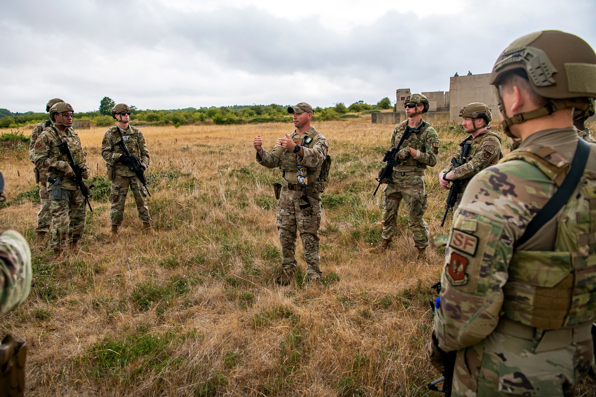 U.S. Air Force Staff Sgt. James Matherly, center, 824th Base Defense Squadron squad leader, gives instruction during a field training exercise at Stanford Training Area, England, Aug. 17, 2022. Instructors from the 820th Base Defense Group and 435th Security Forces Squadron Ground Combat Readiness Training Center, conducted the exercise to evaluate and bolster the combat readiness skills of the defenders from the 423d SFS. (U.S. Air Force photo by Staff Sgt. Eugene Oliver)