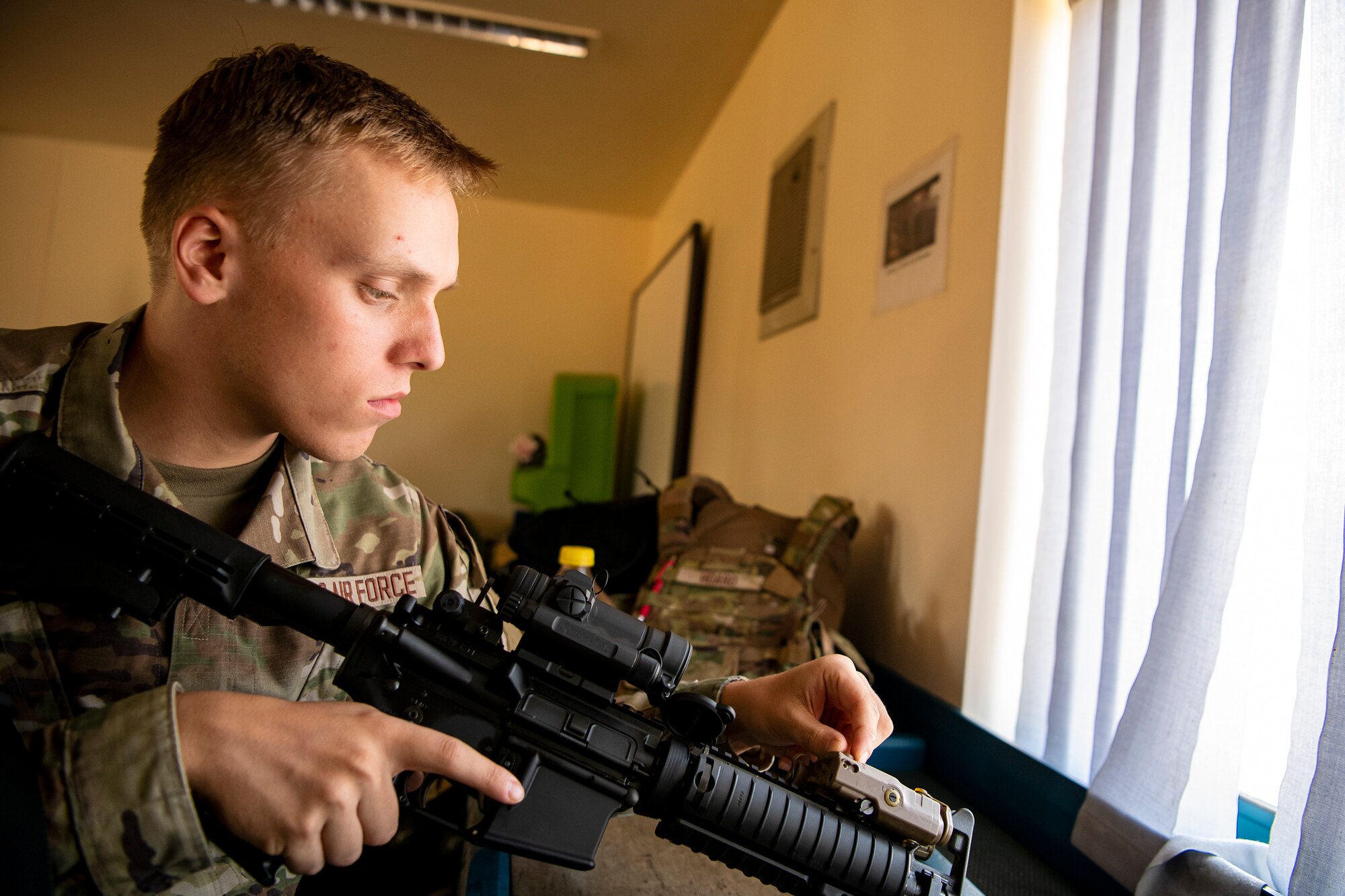 An Airman from the 423d Security Forces Squadron inspects his M4 carbine prior to a proficiency course at RAF Molesworth, England, Aug. 19, 2022. During the course instructors from the 820th Base Defense Group and 435th Contingency Response Group provided oversight and guidance to help critique and advance the combat arms skills of the students in the course. (U.S. Air Force photo by Staff Sgt. Eugene Oliver)