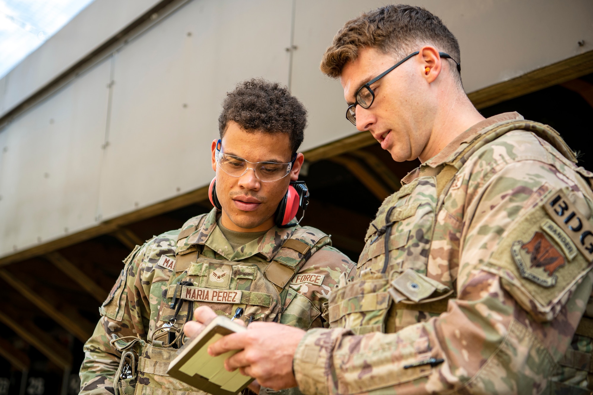 An instructor from the 820th Base Defense Group, right, speaks with Airman 1st Class Richard Maria Perez, 423d Security Forces Squadron flight member, during a proficiency course at RAF Molesworth, England, Aug. 19, 2022. During the course instructors from the 820th Base Defense Group and 435th Contingency Response Group provided oversight and guidance to help critique and advance the combat arms skills of the defenders from the 423d SFS. (U.S. Air Force photo by Staff Sgt. Eugene Oliver)