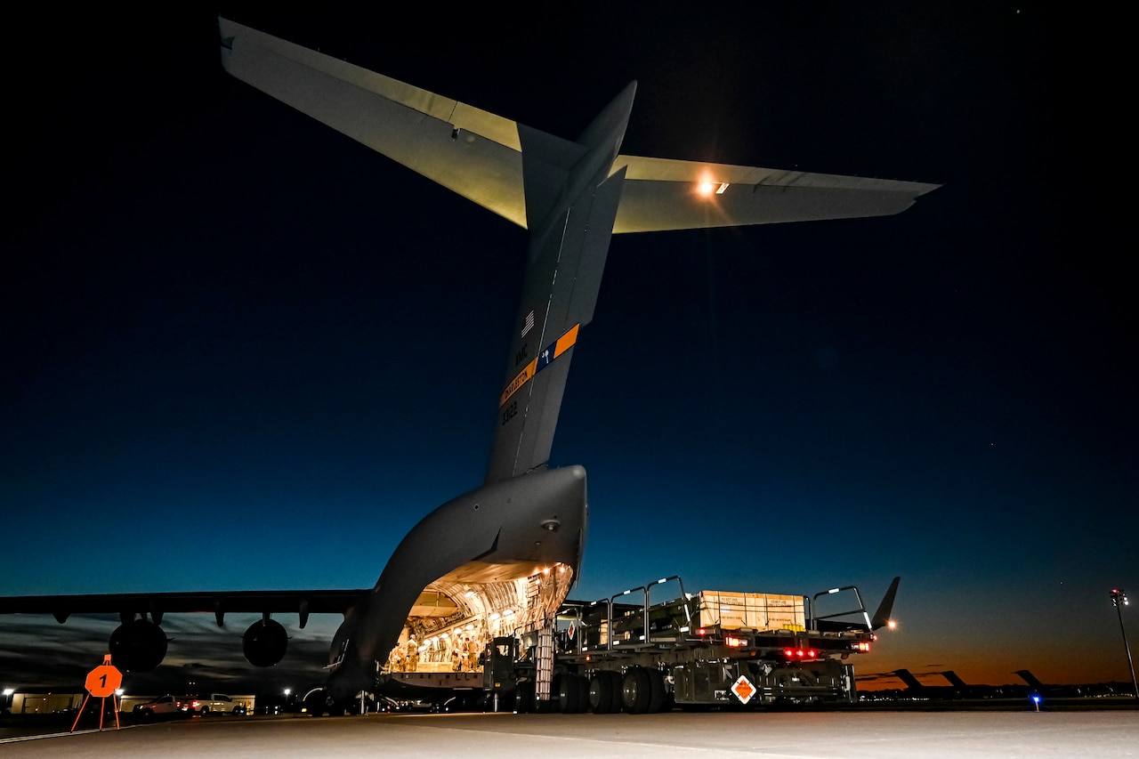 A military aircraft sits on the flight deck at night.