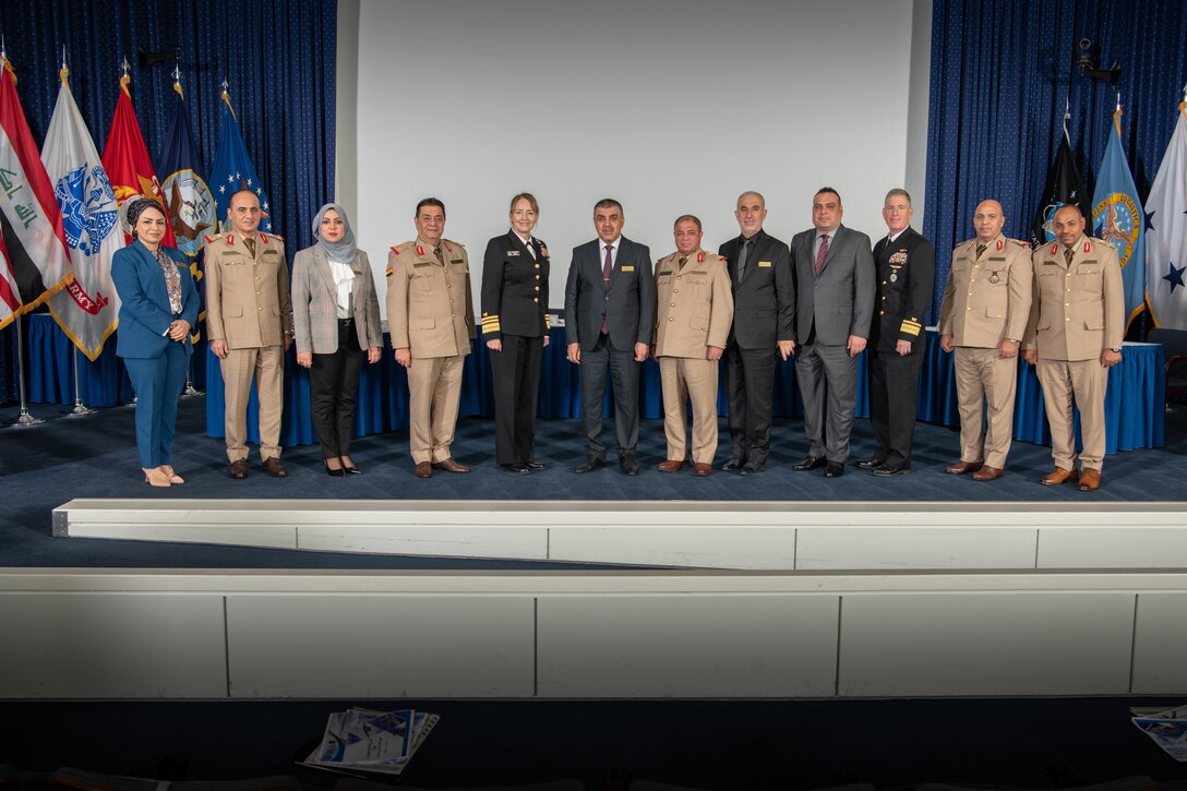 Twelve people - three of them women - stand side by side on a stage.