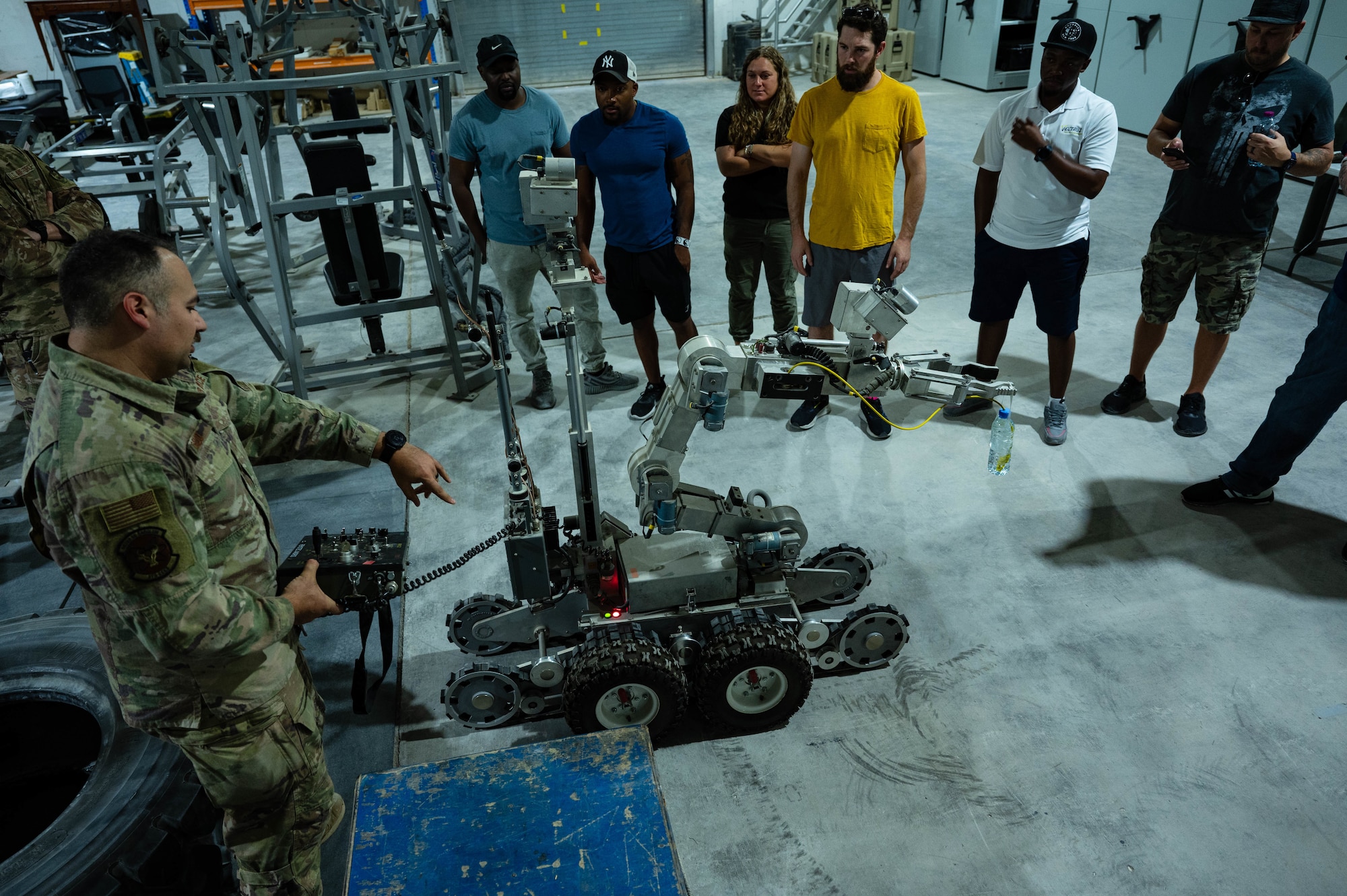 U.S. Air Force Tech Sgt. Jason Calio, an explosive ordinance technician, 379th Expeditionary Civil Engineer Squadron demonstrates using a robot used to disarm explosive devices, AUG 8, 2022 at Al Udeid Air Base, Qatar. Calio said that the water bottle on the end of the robotic arm is a cheap and effective way of helping to neutralize threats. (U.S. Air Force photo by Staff Sgt. Dana Tourtellotte)