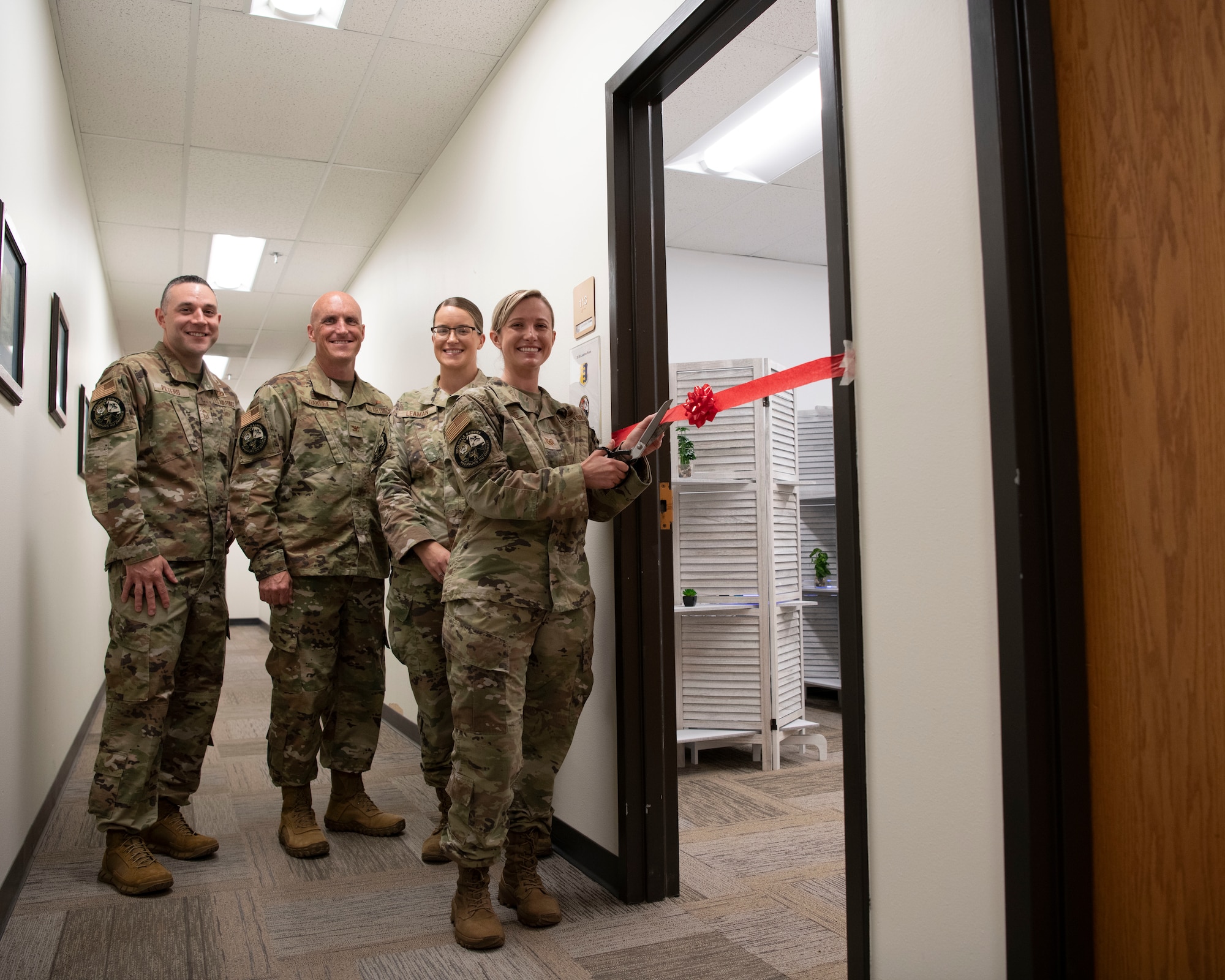 Service members assigned to the 28th Bomb Wing Headquarters prepare to cut a ribbon symbolizing the grand opening of the lactation room within the headquarters building at Ellsworth Air Force Base, S.D., Aug. 1, 2022.
