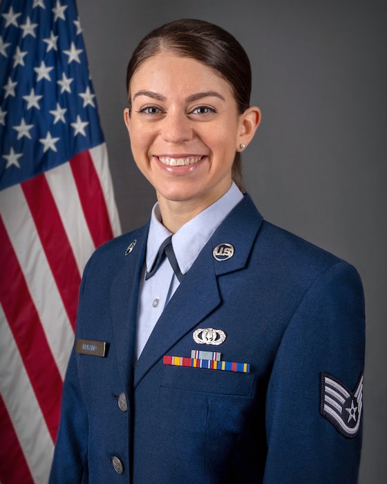 An official headshot of SSgt Andrea Murano in front of the American flag. She is wearing the blue service dress uniform.