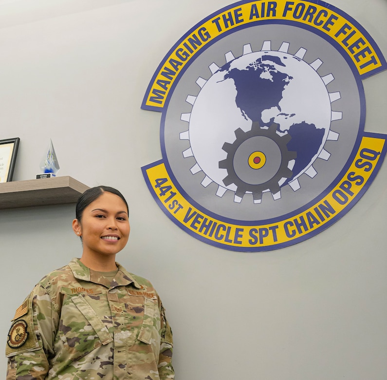 U.S. Air Force Tech. Sgt. Jennifer Gloria “JT” Thomas, 441st Vehicle Support Chain Operations Squadron, noncommissioned officer in charge of vehicle disposition and lease management, stands under the 441st VSCOS seal at Joint Base Langley-Eustis, Virginia.