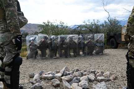 A rank of soldiers crouch behind their shields as another group of soldiers toss rocks at them