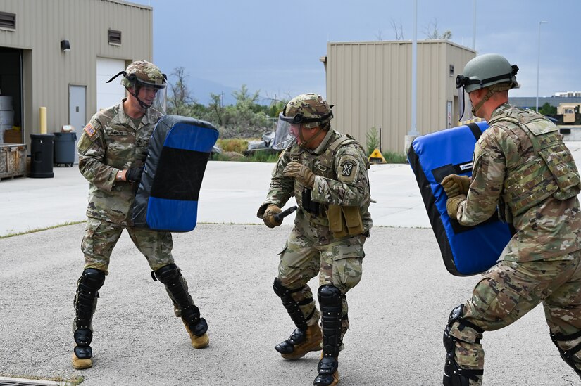 A  soldier  uses a baton to engage two simulated adversaries.