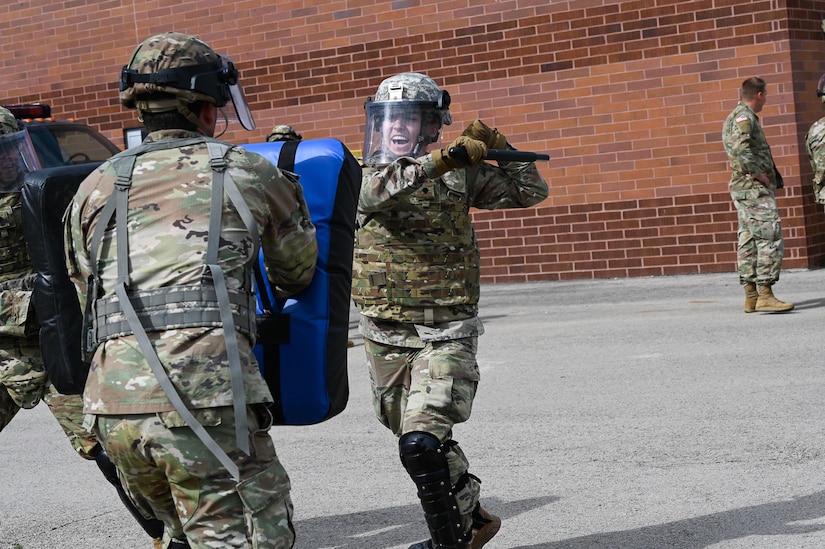 A  soldier  uses a baton to engage two simulated adversaries.