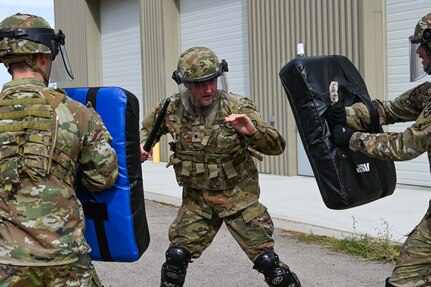 A  soldier  uses a baton to engage two simulated adversaries.