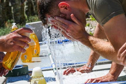 A soldier washes his eyes out with water after being sprayed with OC spray.