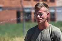 A soldier with eyes closed is sprayed with OC spray.