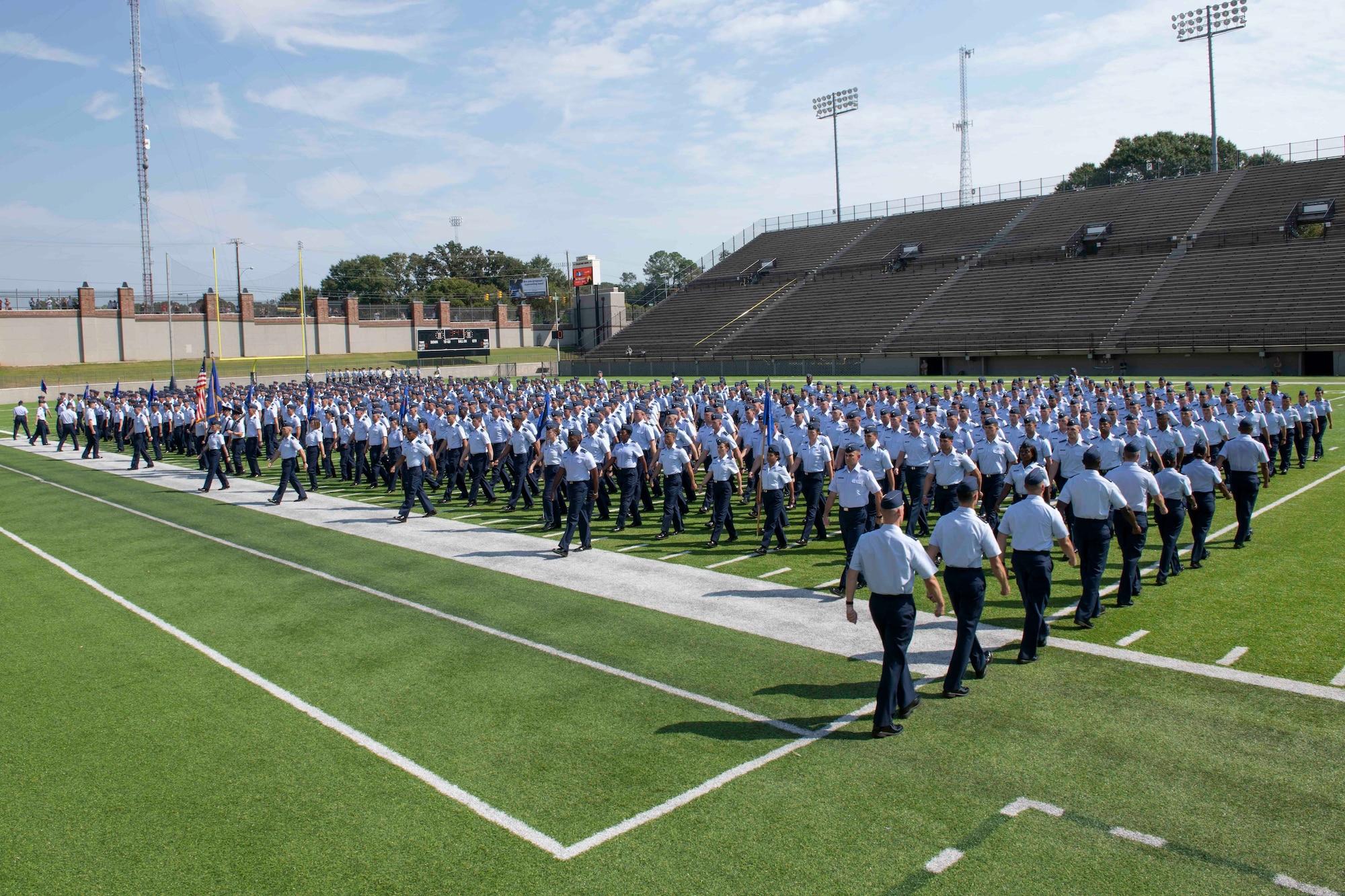 A formation of officers march into formation at a stadium.